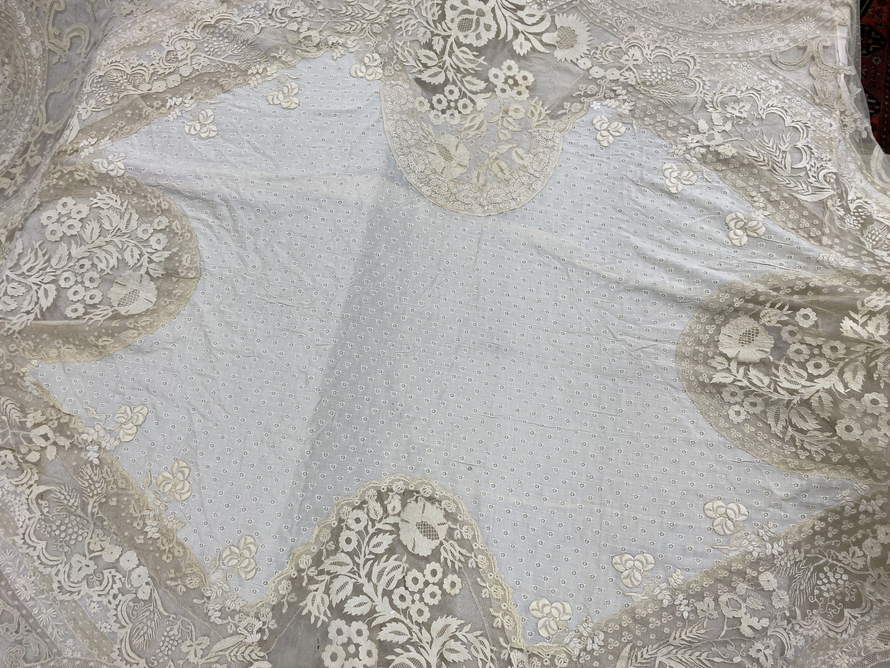 An Edwardian hand made lace bedspread. Hand sewn using finely spun lawn, decorated with Carrickmacross and white work embroidery, edged in bobbin lace. Possibly made as part of a trousseau.